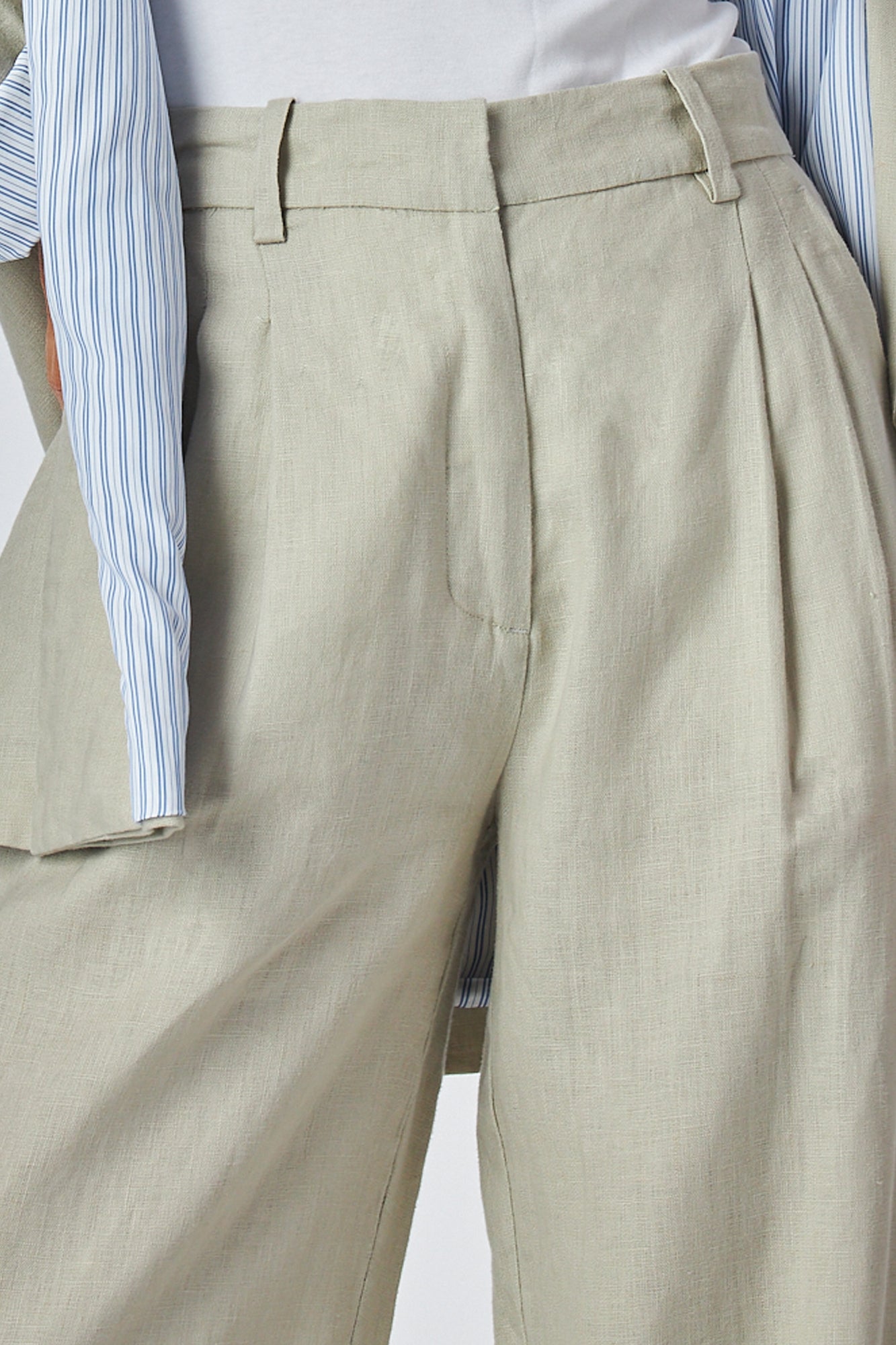Close-up of beige pleated pants worn with a casual blazer
