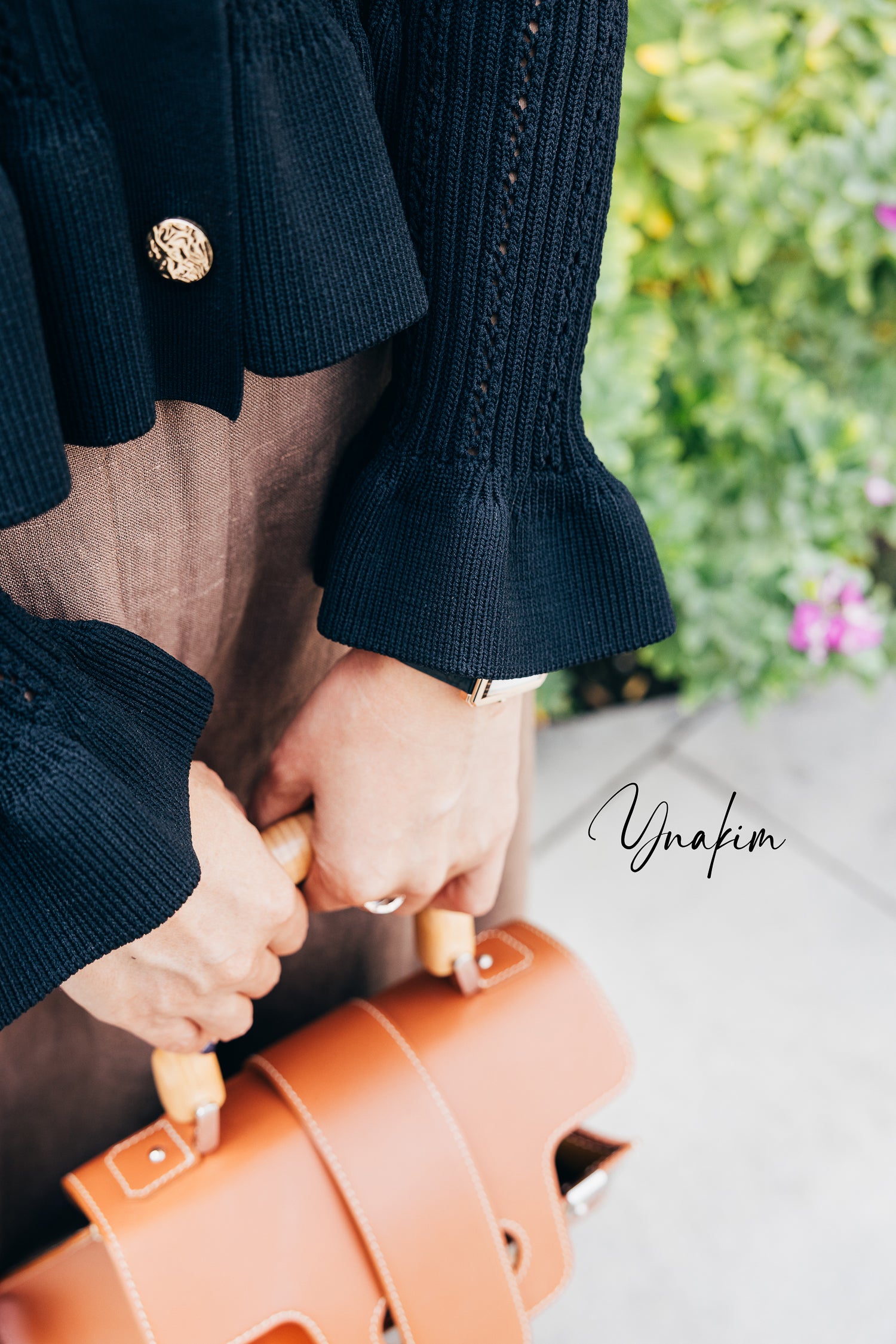 Model holding an orange suitcase with a peplum black top