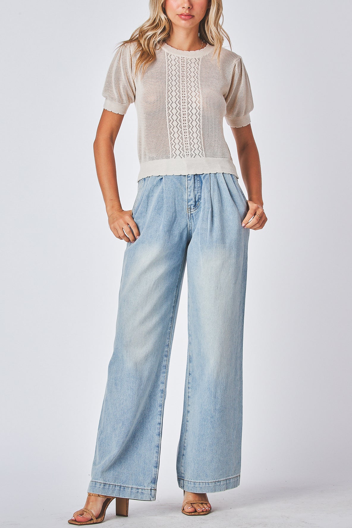 Model wearing a light-color top and light blue wash wide-leg jeans on a plain background