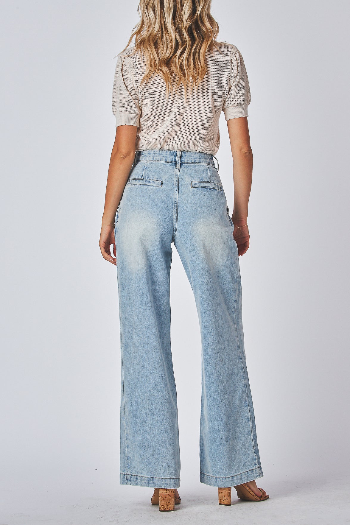 Model wearing light blue relax fit jeans and a beige t-shirt on a plain background