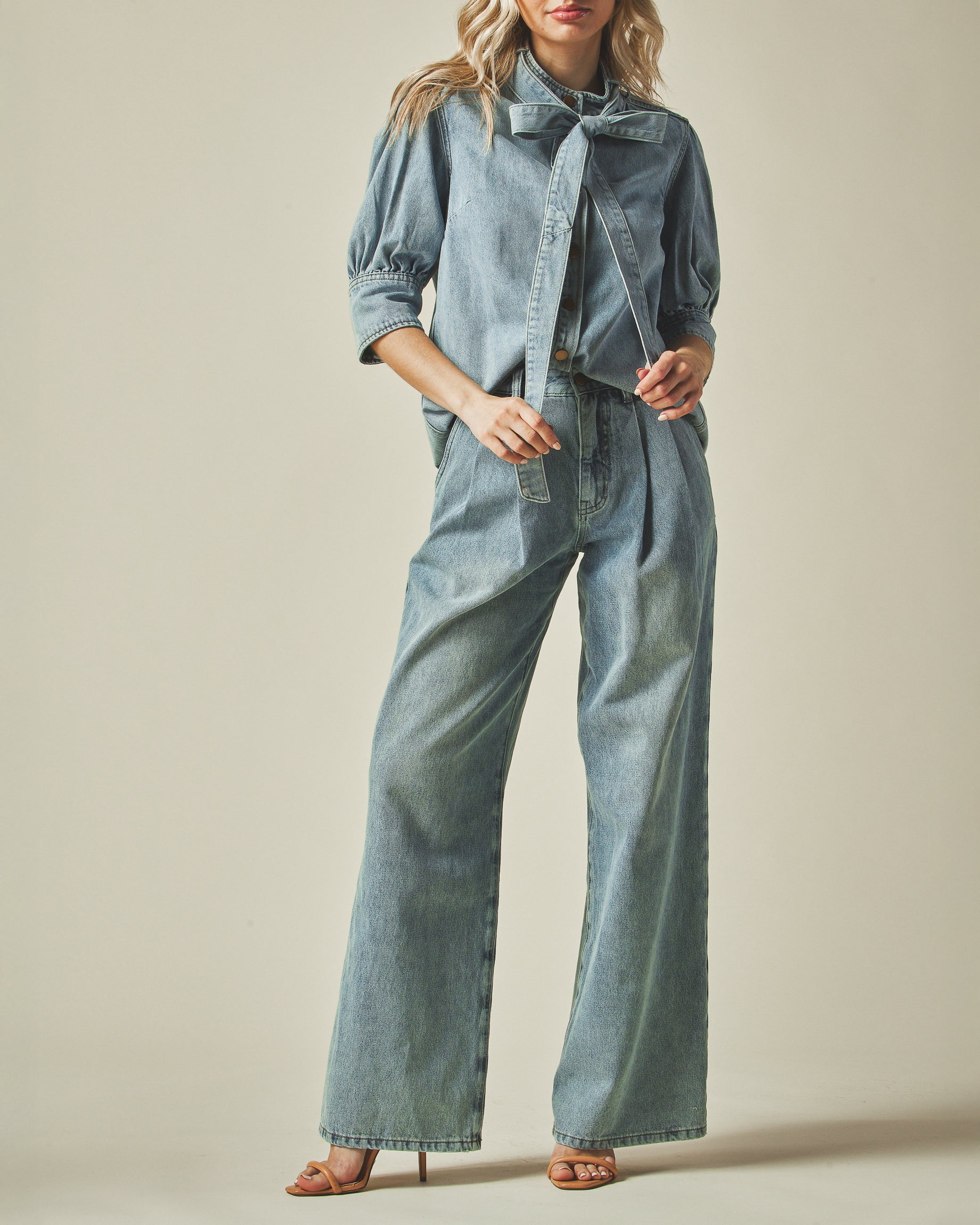 Model wearing a denim outfit with wide-leg pants on a neutral background