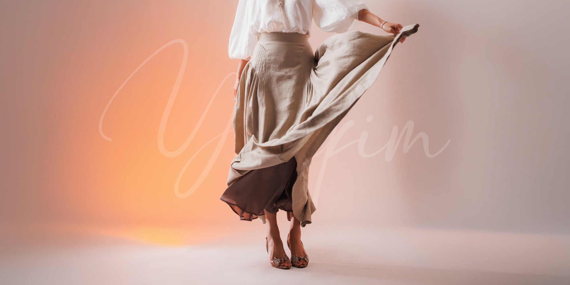 Model wearing a flowing skirt against a gradient background