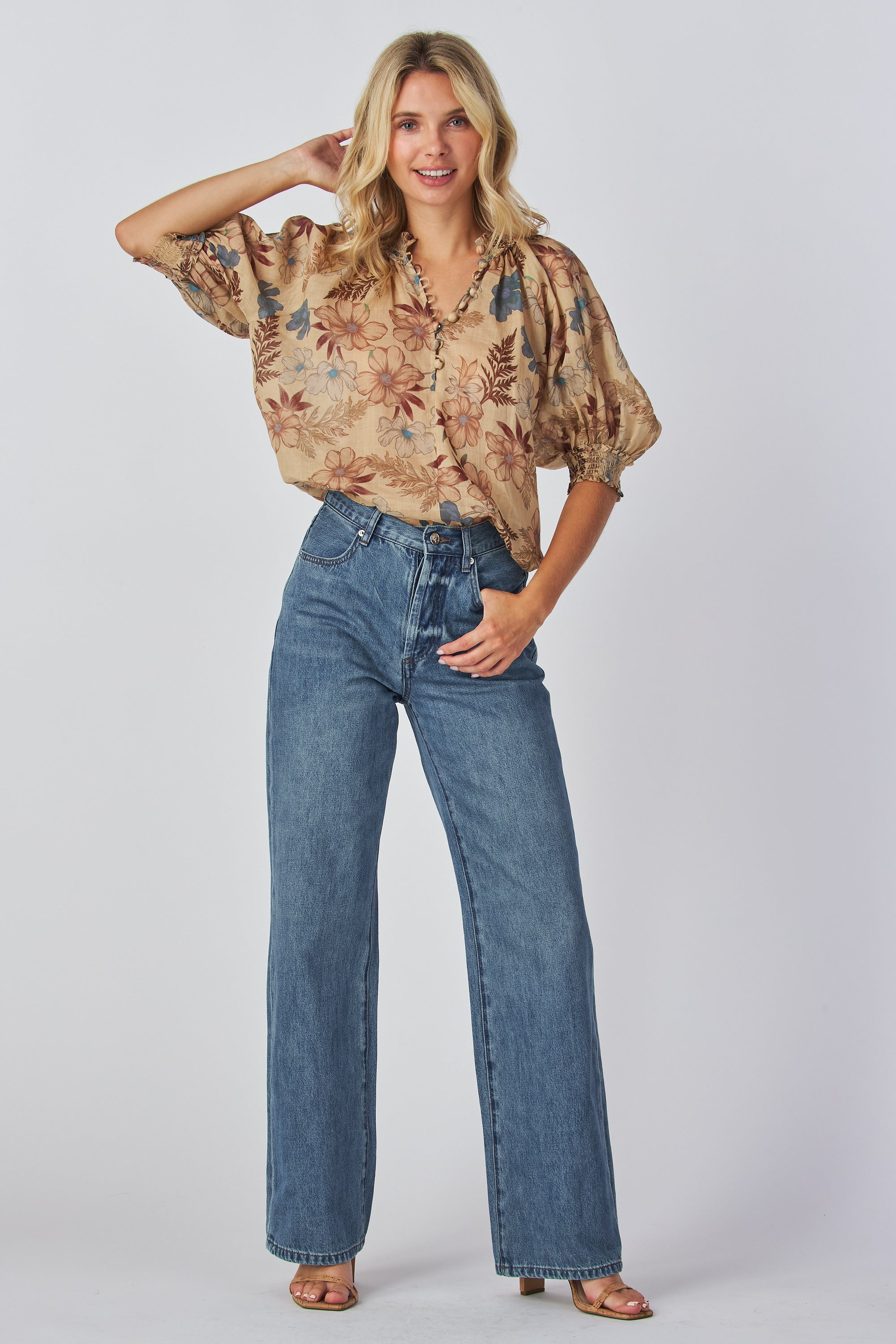 jeans are a classic high-waisted, straight-leg style in a medium blue wash. The fabric has a slightly vintage, lived-in look with subtle fading around the button fly and hip area, giving it a naturally worn effect without heavy distressing. High-rise fit with belt loops,