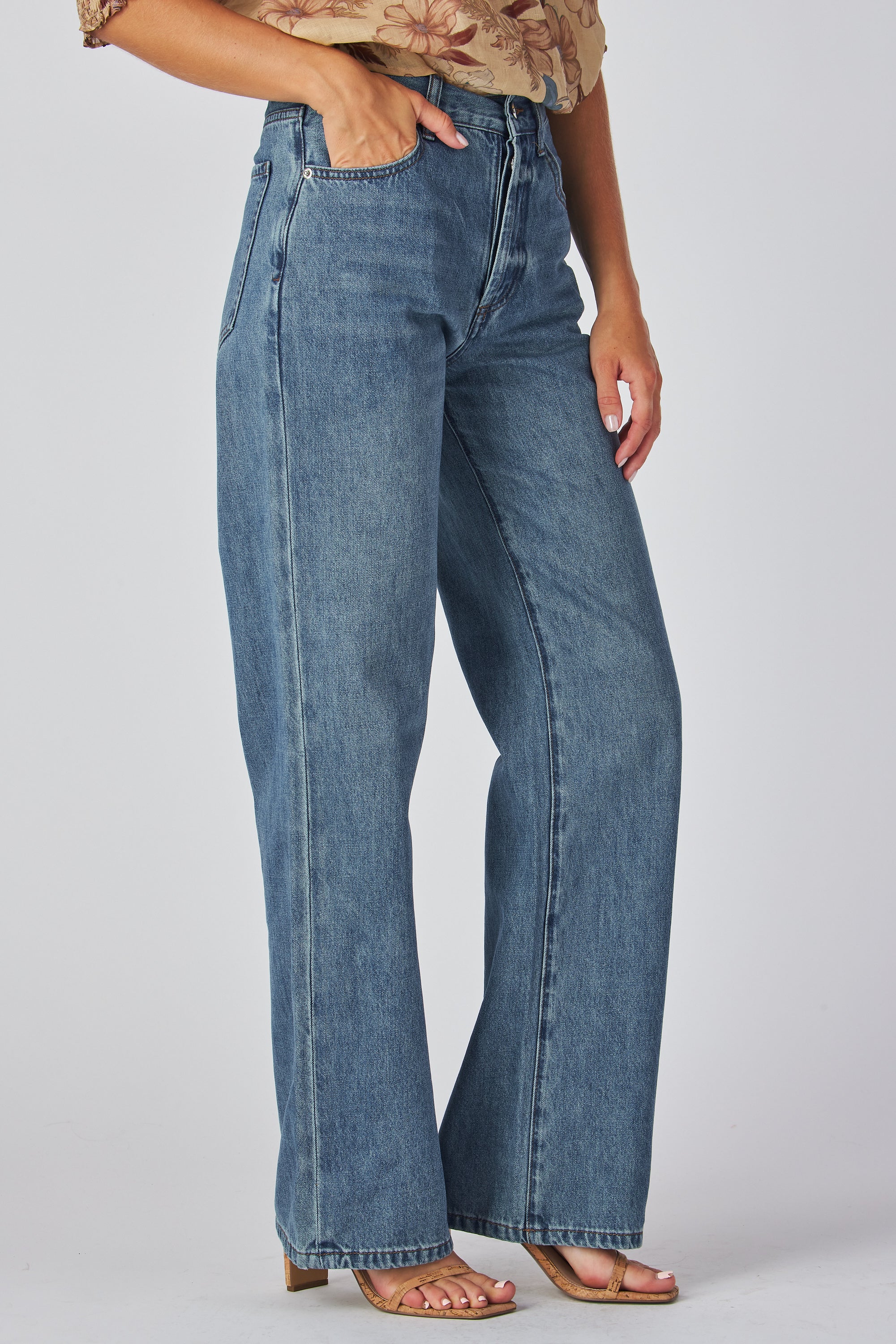 jeans are a classic high-waisted, straight-leg style in a medium blue wash. The fabric has a slightly vintage, lived-in look with subtle fading around the button fly and hip area, giving it a naturally worn effect without heavy distressing. High-rise fit with belt loops,