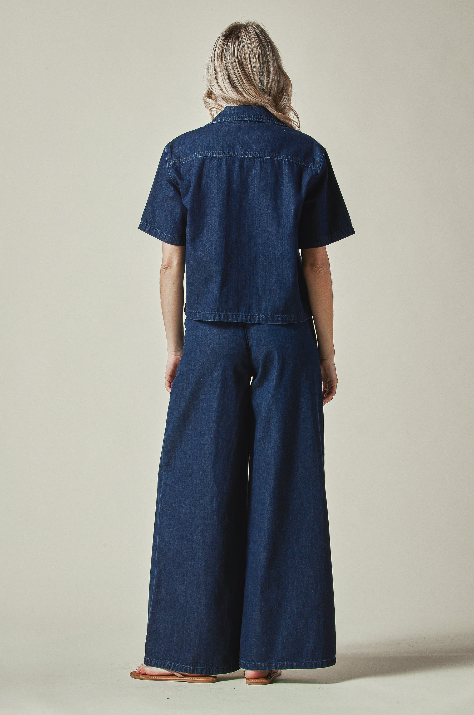 Model wearing a blue denim outfit on a plain background