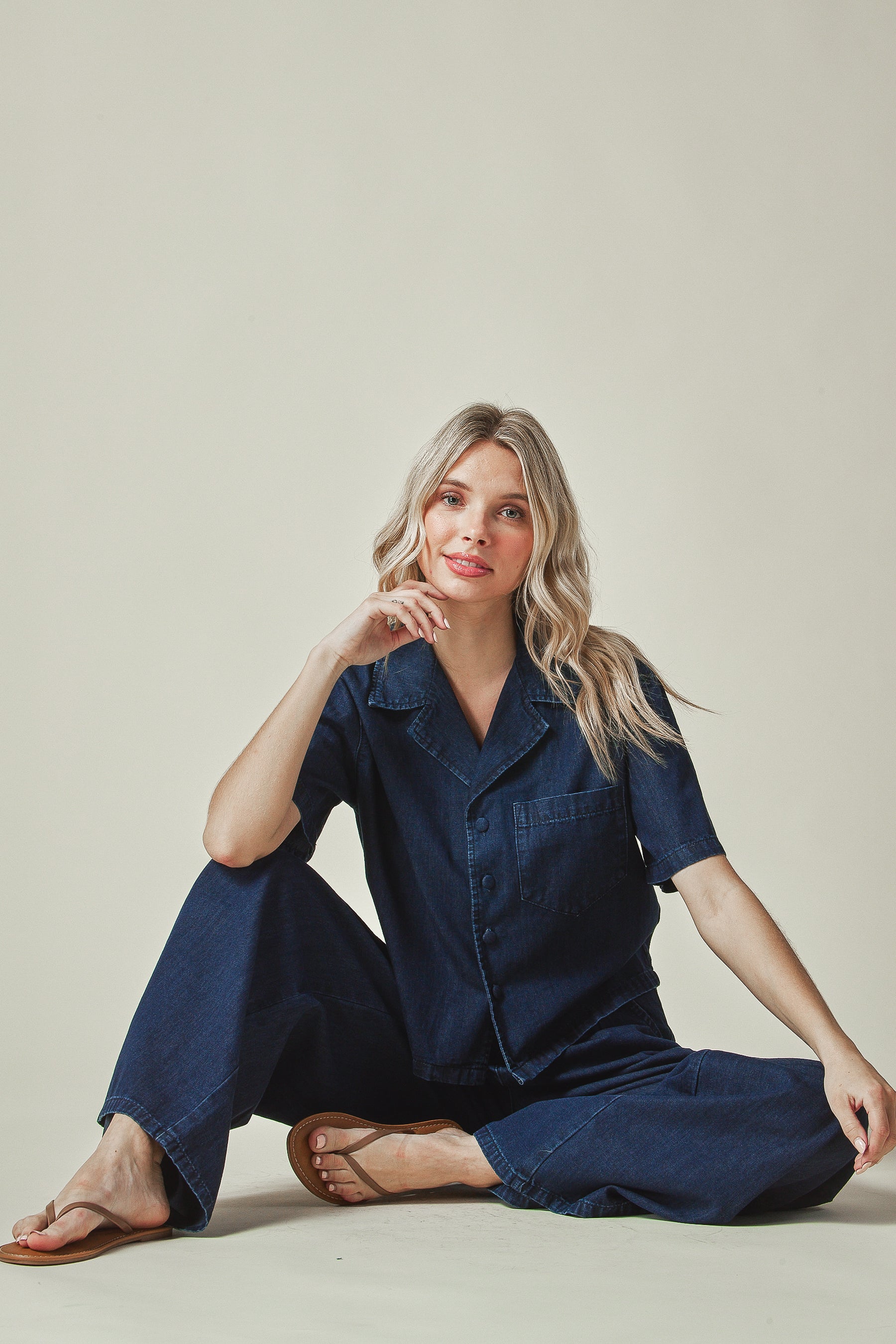 Model wearing a navy blue denim set outfit sitting on the floor