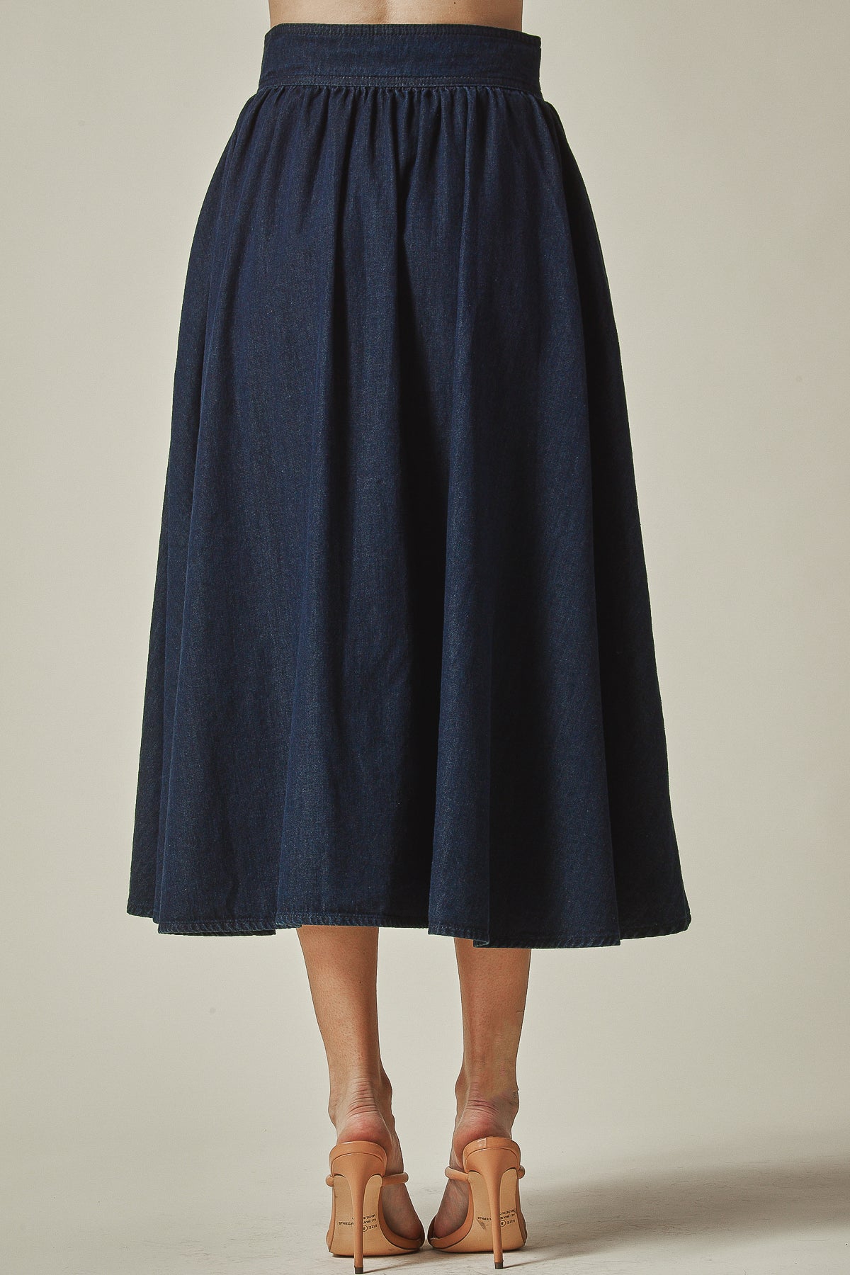 Model wearing navy blue skirt standing on  the wall