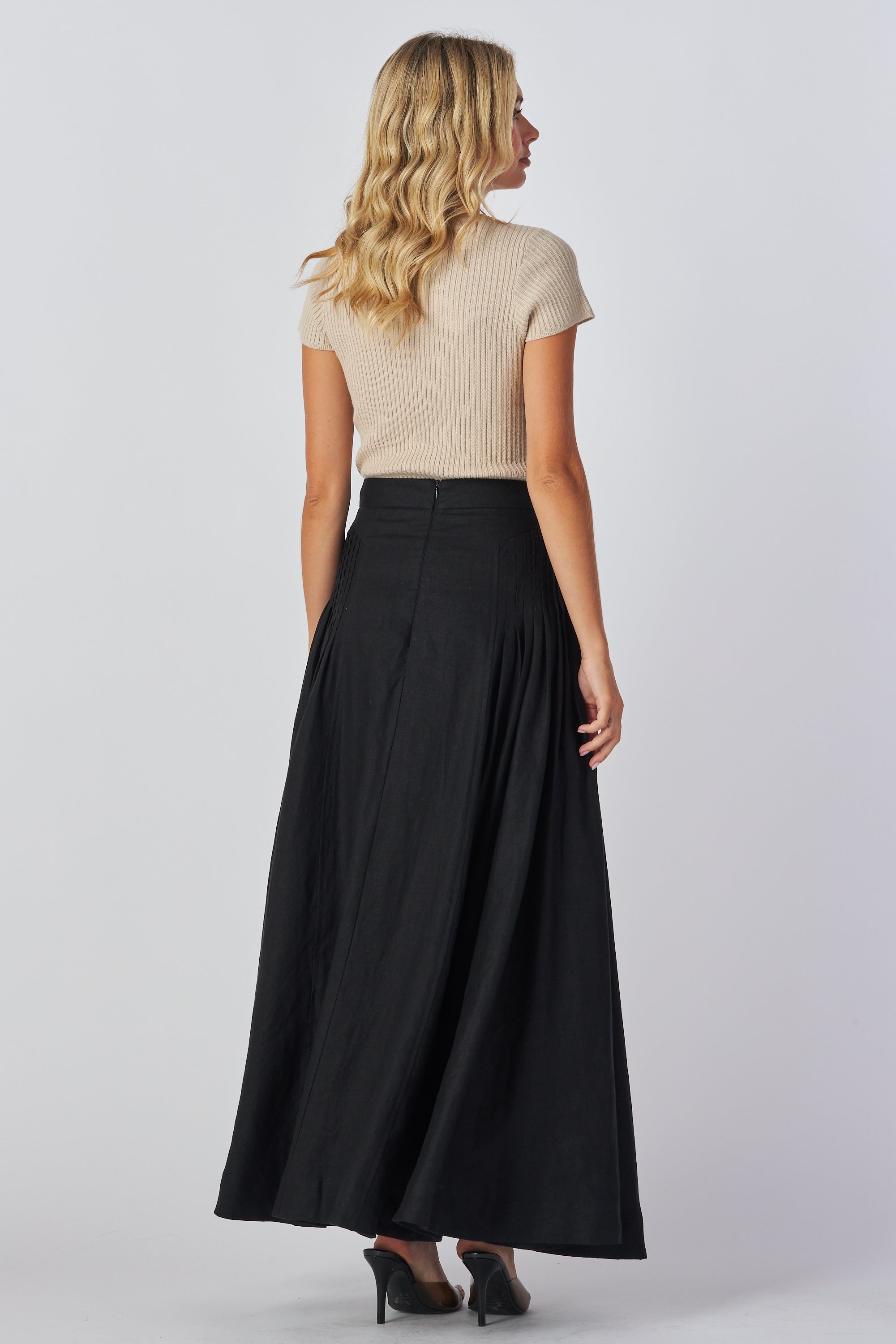 Woman wearing a beige top and black skirt on a white background