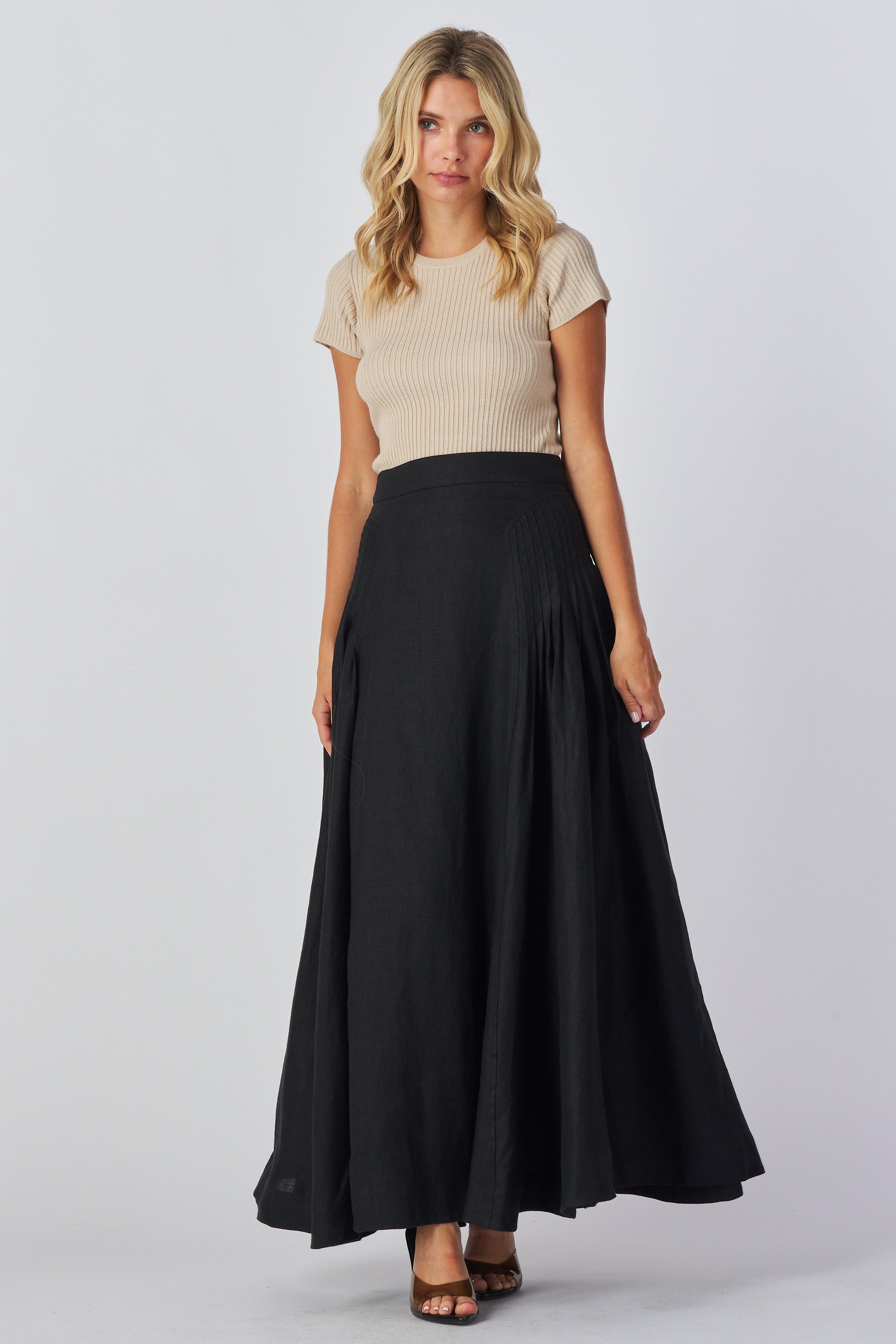 Woman wearing a beige top and black skirt on a white background