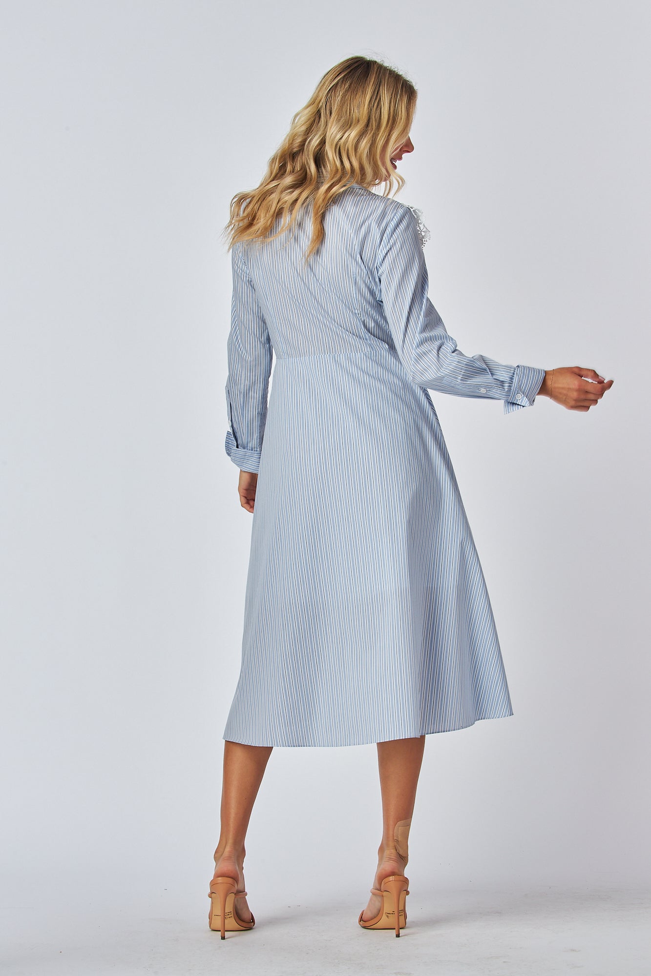 Model in a light blue and white striped shirt dress with a traditional collar and long sleeves, featuring white lace applique on the chest area. The dress has a flared A-line silhouette and is midi-length.