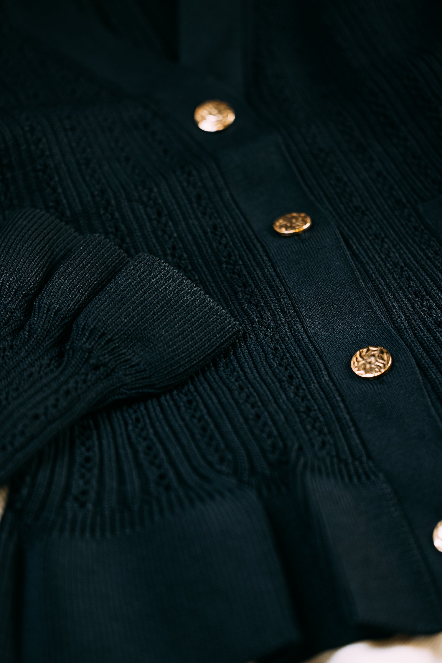 Close-up of a black peplum top with gold buttons