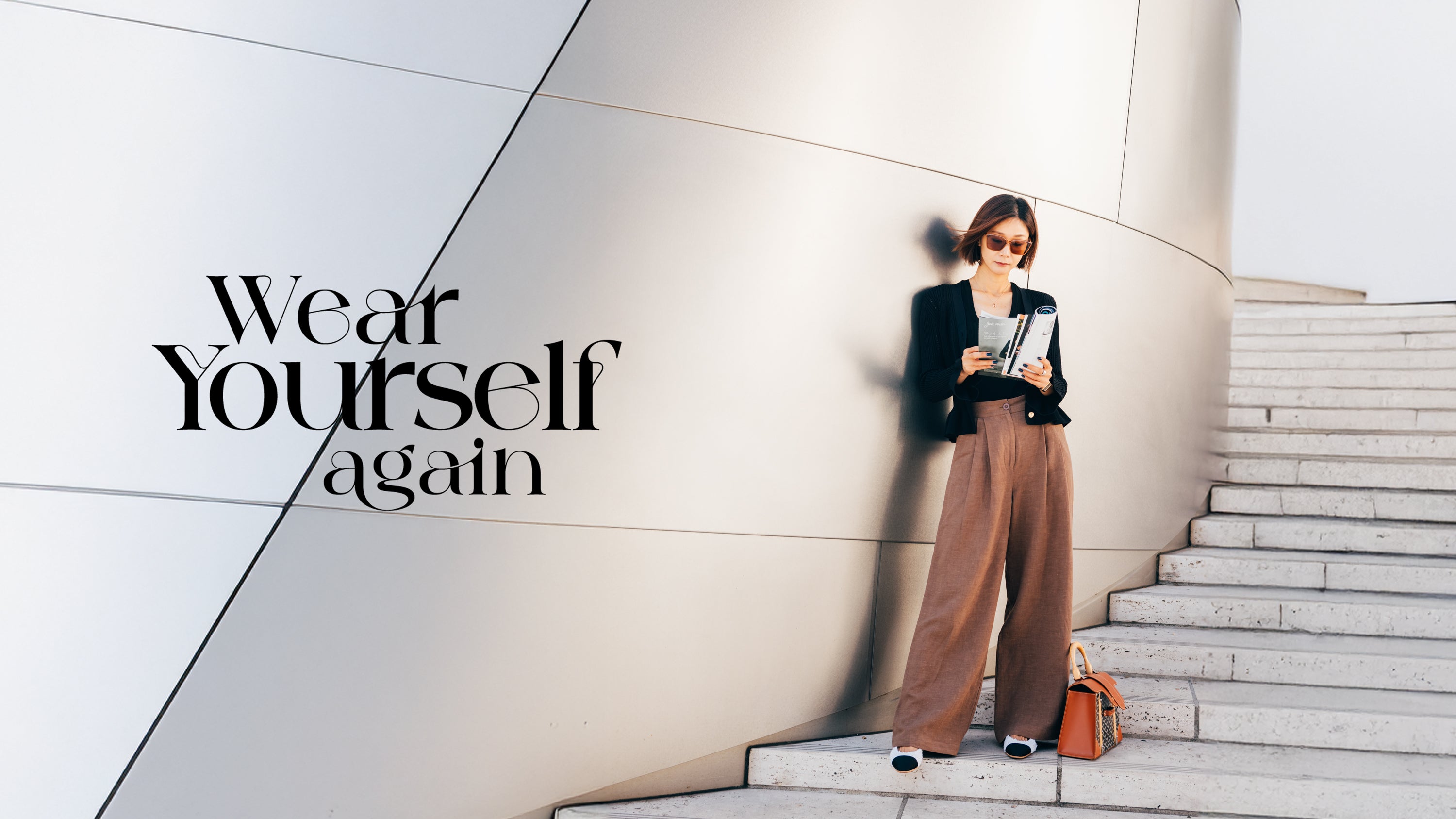 Woman standing on a staircase with text 'Wear Yourself Again' in an urban setting.